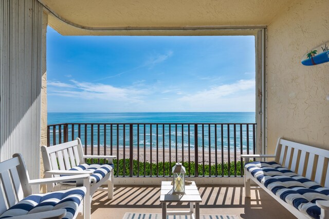 balcony featuring a beach view and a water view