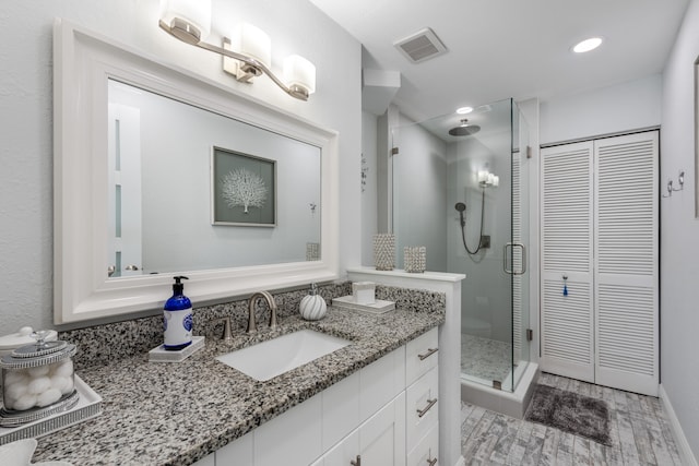 bathroom featuring a shower with shower door and vanity