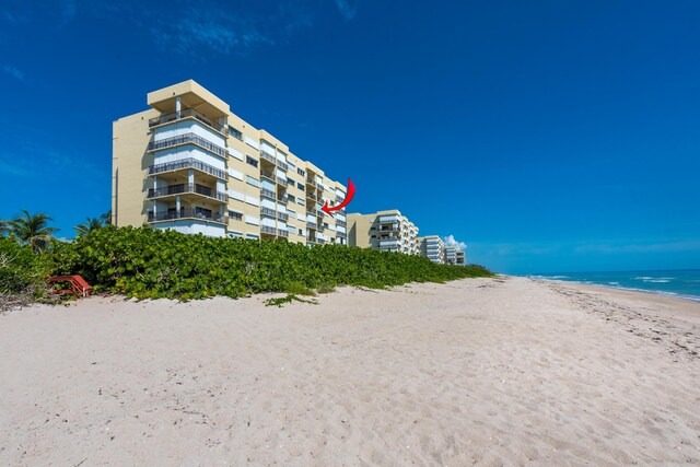 view of property with a water view and a beach view