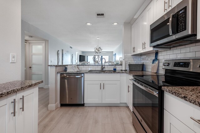 kitchen featuring sink, light wood-type flooring, dark stone counters, and stainless steel appliances