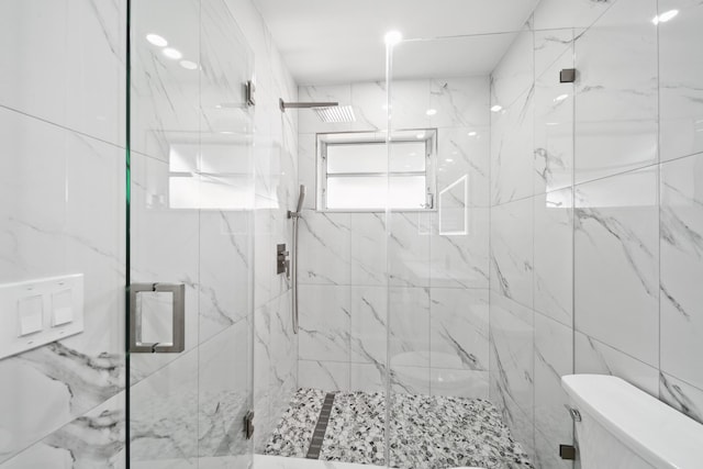 bathroom with tile walls, a shower with door, and toilet