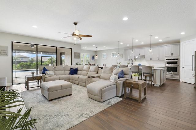 living room with sink, a textured ceiling, dark wood-type flooring, and ceiling fan