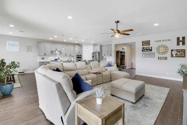 living room featuring sink, wood-type flooring, and ceiling fan