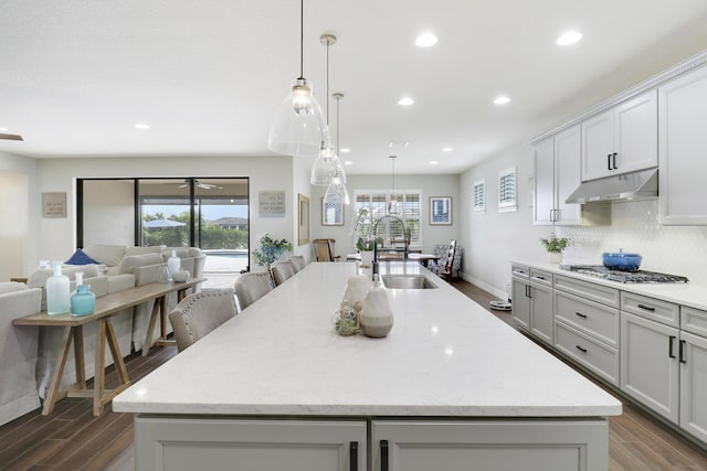 kitchen with an island with sink, sink, dark hardwood / wood-style flooring, and decorative light fixtures