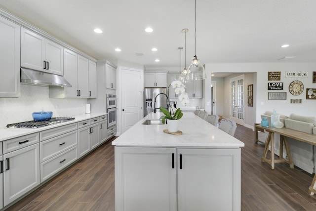 kitchen with sink, decorative light fixtures, light stone countertops, a kitchen island with sink, and decorative backsplash