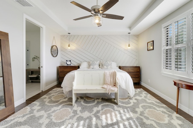 bedroom with dark wood-type flooring, ceiling fan, a raised ceiling, and wood walls