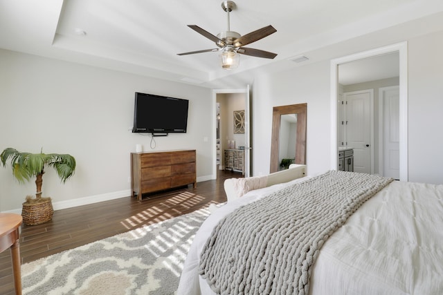 bedroom featuring a raised ceiling, dark wood-type flooring, and ceiling fan