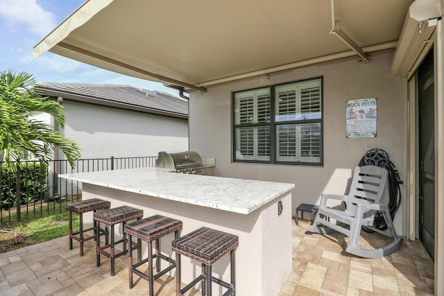 view of patio with grilling area, an outdoor bar, and exterior kitchen