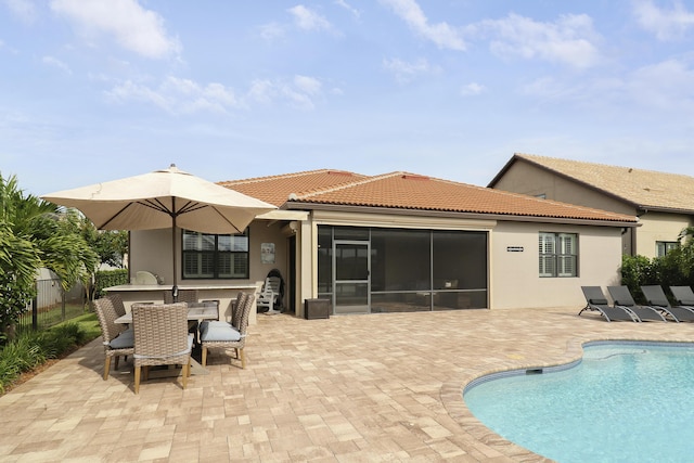 back of property featuring exterior bar, a fenced in pool, a patio area, and a sunroom