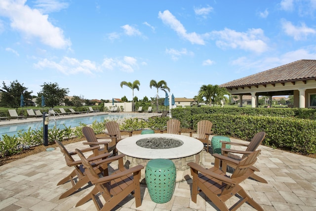 view of patio with a community pool and an outdoor fire pit