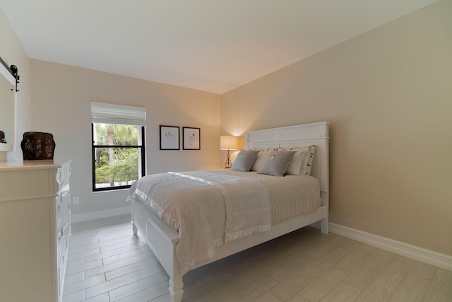 bedroom with light hardwood / wood-style floors and a barn door