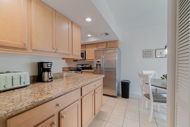 kitchen featuring light tile patterned flooring, light stone countertops, appliances with stainless steel finishes, and light brown cabinetry