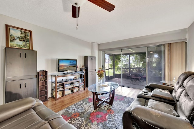 living room with light hardwood / wood-style flooring, a textured ceiling, and ceiling fan