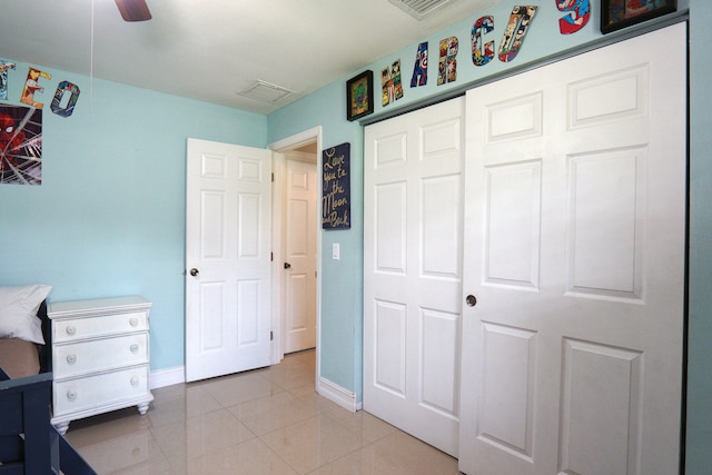 bedroom featuring ceiling fan, light tile patterned flooring, and a closet