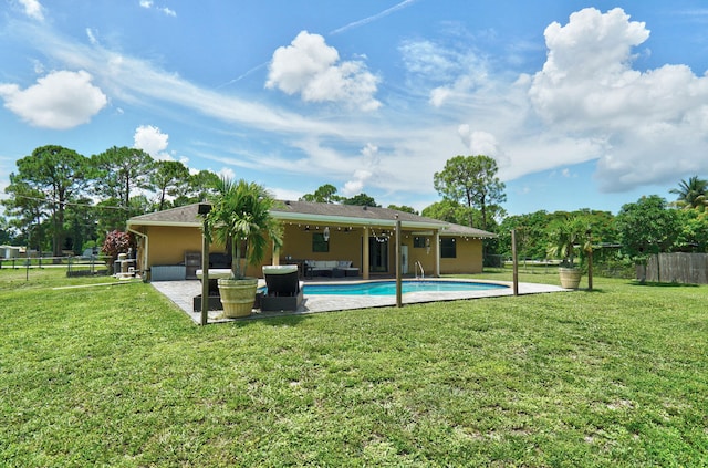 rear view of property featuring a lawn, a patio area, and a fenced in pool