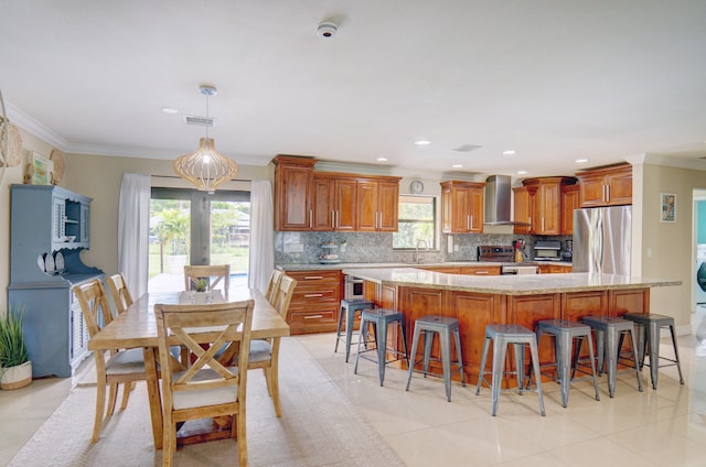 kitchen with decorative backsplash, stainless steel appliances, a kitchen island, and wall chimney exhaust hood