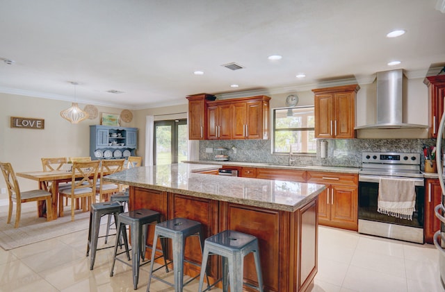 kitchen with a kitchen breakfast bar, plenty of natural light, stainless steel range with electric stovetop, and wall chimney exhaust hood