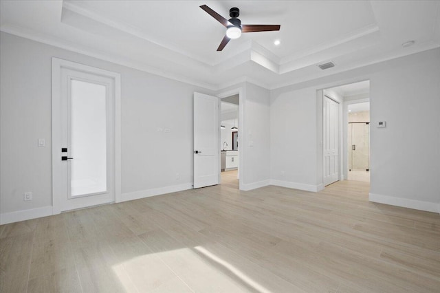 unfurnished bedroom featuring ornamental molding, ceiling fan, light wood-type flooring, and a tray ceiling