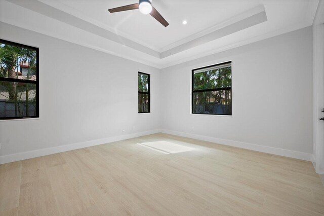 spare room with ceiling fan, light hardwood / wood-style flooring, and a tray ceiling