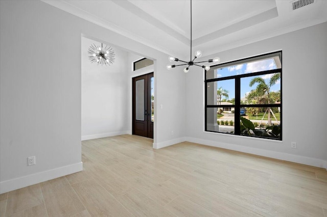 unfurnished room featuring a raised ceiling, light wood-type flooring, and a chandelier