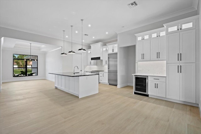 kitchen with pendant lighting, premium appliances, white cabinetry, and wine cooler