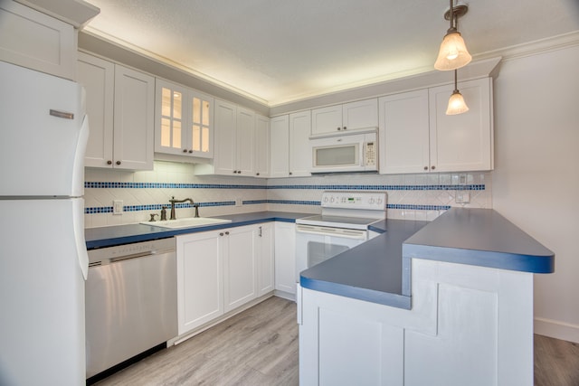 kitchen with white appliances, light wood-type flooring, backsplash, pendant lighting, and sink