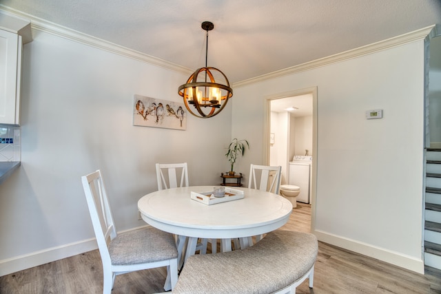 dining room featuring ornamental molding, light hardwood / wood-style flooring, an inviting chandelier, and washer / dryer