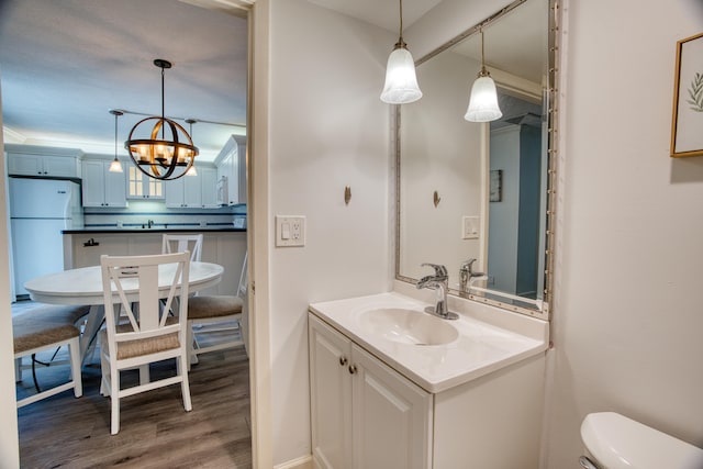 bathroom with an inviting chandelier, vanity, wood-type flooring, and toilet