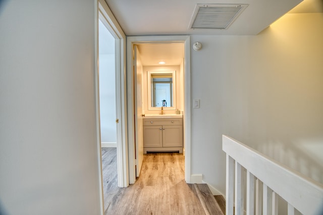 corridor featuring sink and light wood-type flooring