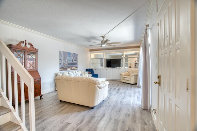 living room with light wood-type flooring, ceiling fan, ornamental molding, and a textured ceiling