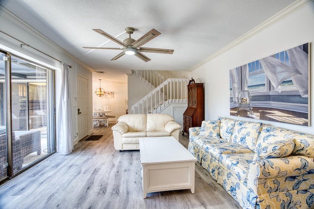 living room featuring light wood-type flooring, ceiling fan with notable chandelier, ornamental molding, and a textured ceiling