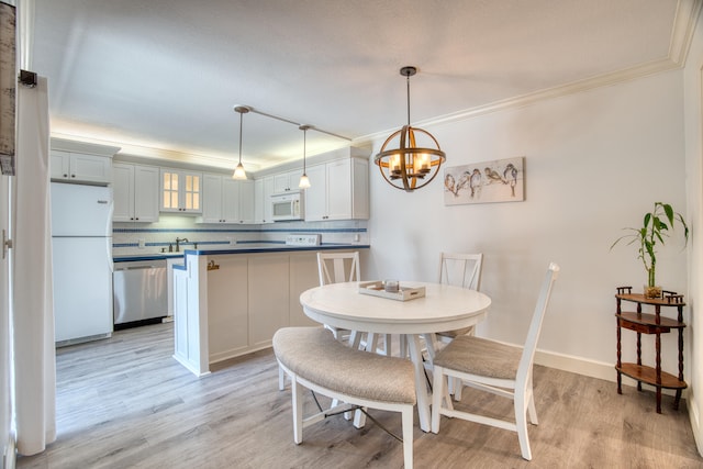 dining room featuring an inviting chandelier, sink, crown molding, and light wood-type flooring