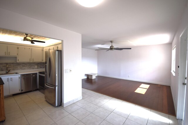 kitchen featuring ceiling fan, tasteful backsplash, stainless steel appliances, and light tile patterned floors