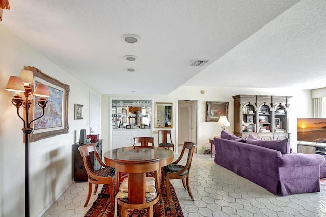 dining area featuring light tile patterned flooring and a textured ceiling