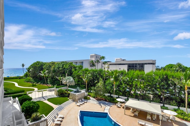 view of pool featuring a water view, a patio, and a yard