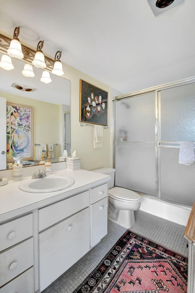 bathroom featuring a shower with shower door, tile patterned floors, toilet, and vanity