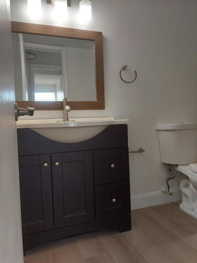 bathroom with hardwood / wood-style floors, vanity, and toilet