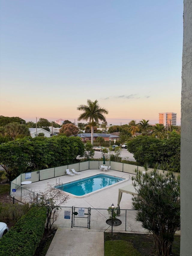 pool at dusk featuring a patio