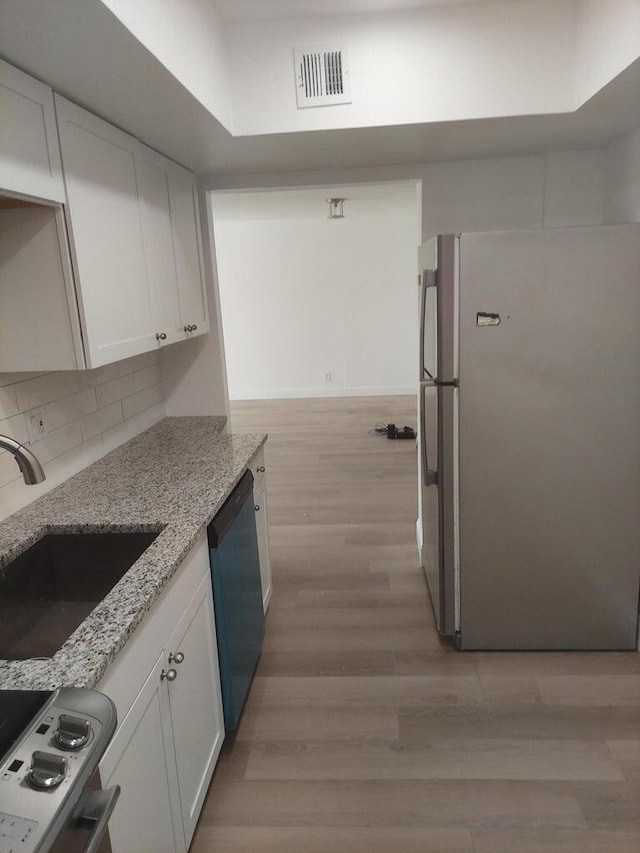 kitchen with white cabinets, dishwashing machine, stainless steel fridge, and sink