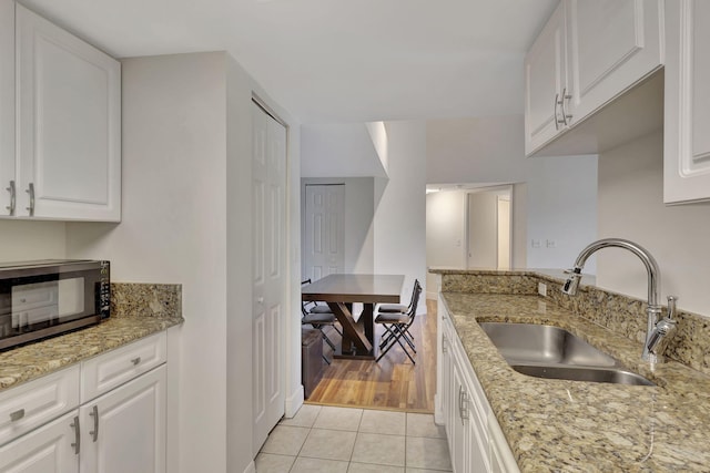 kitchen featuring white cabinetry, sink, light tile patterned flooring, and light stone countertops