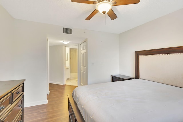 bedroom with hardwood / wood-style floors, connected bathroom, and ceiling fan