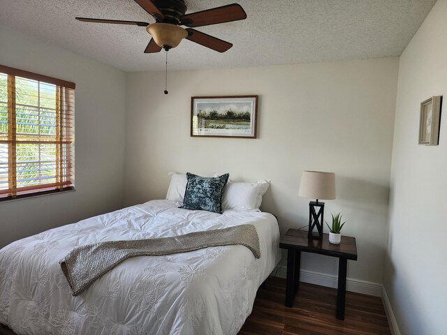 bedroom with ceiling fan, dark hardwood / wood-style flooring, and a textured ceiling