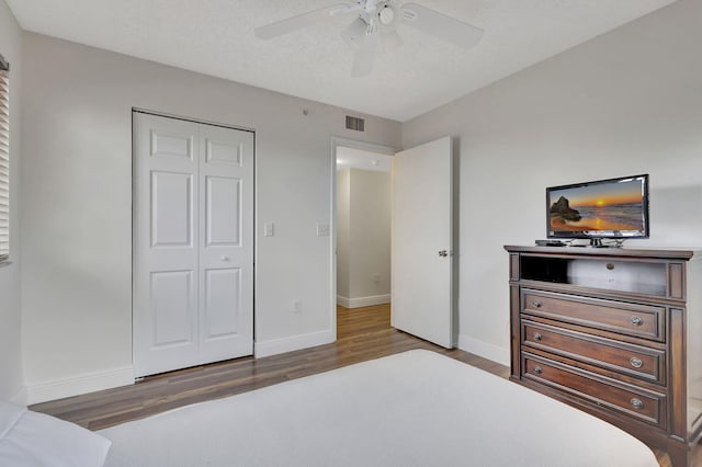 bedroom featuring a textured ceiling, a closet, ceiling fan, and dark wood-type flooring