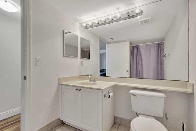 bathroom with tile patterned flooring, vanity, toilet, and walk in shower