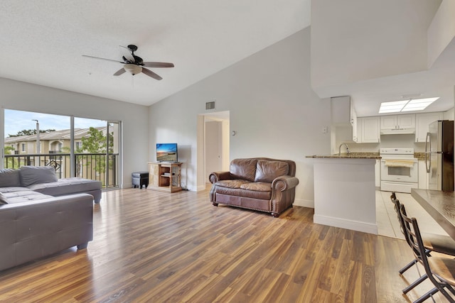 living room with dark hardwood / wood-style floors, vaulted ceiling, ceiling fan, and sink