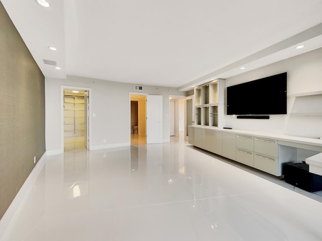 unfurnished living room with built in desk and light tile patterned floors