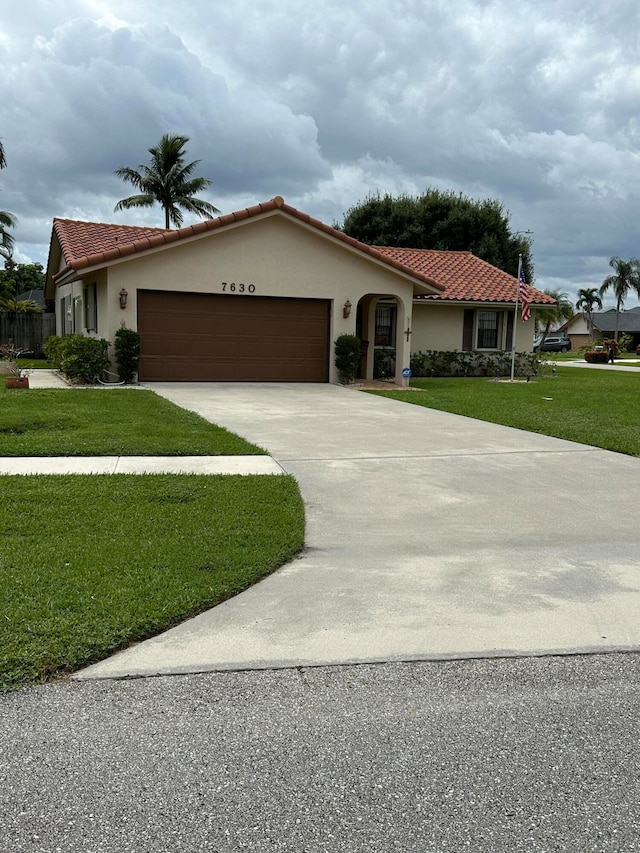 mediterranean / spanish house featuring a front yard and a garage