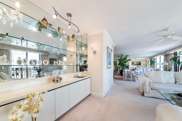 bar featuring sink, white cabinets, light carpet, crown molding, and ceiling fan