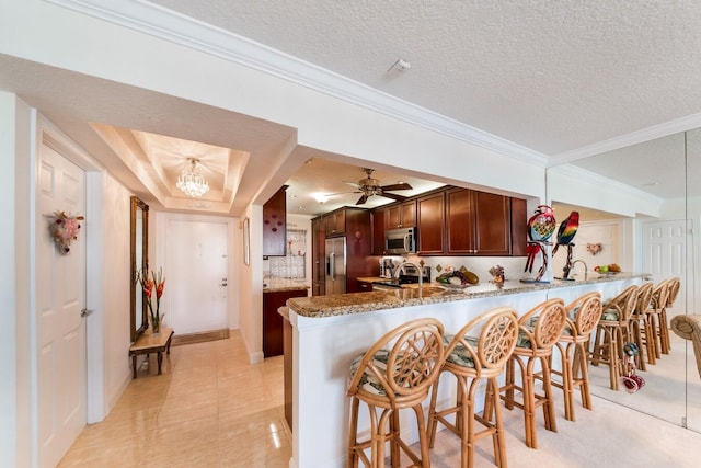 kitchen with ceiling fan with notable chandelier, a textured ceiling, stainless steel appliances, and kitchen peninsula