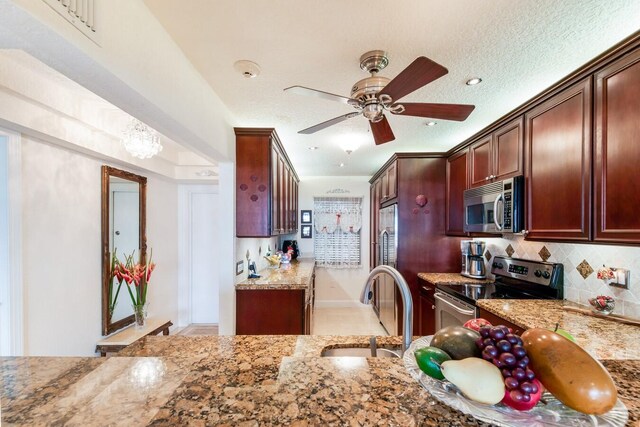 kitchen with ceiling fan, a textured ceiling, appliances with stainless steel finishes, and light stone counters